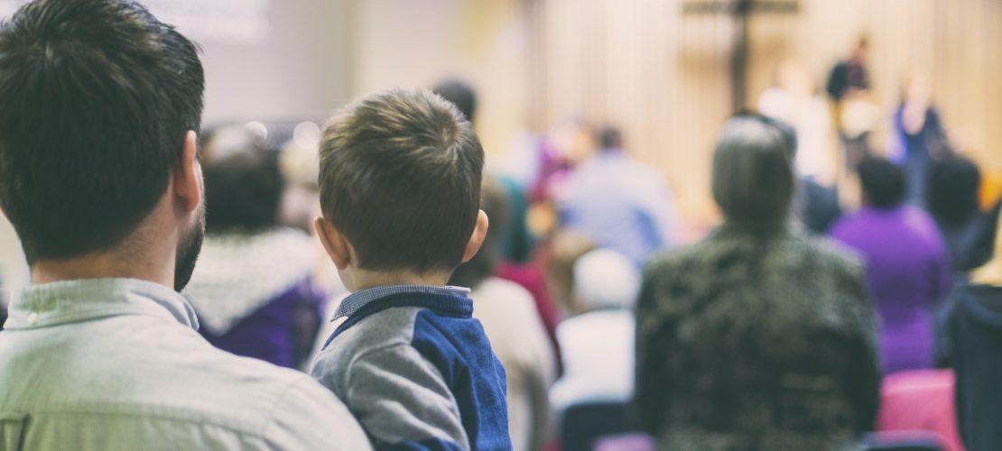 Father with his son participate at christian congregation worship